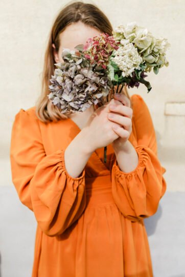 Woman holding flowers in orange dress.